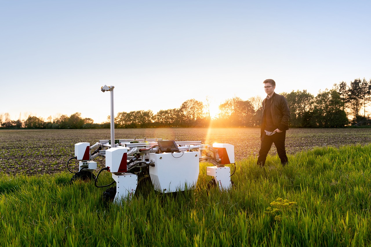 Man walking behind robot in field
