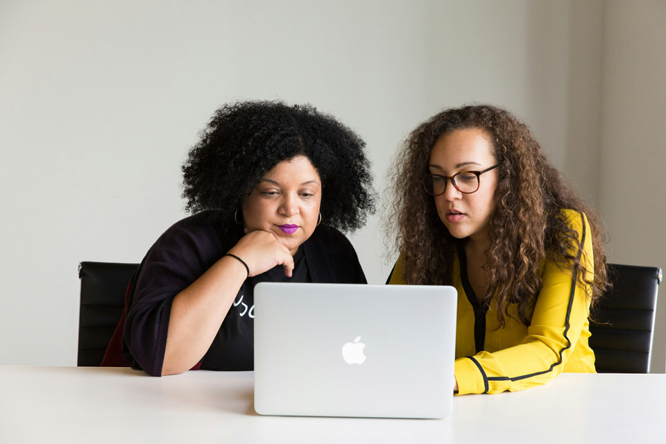 Two women at a desk in front of a computer