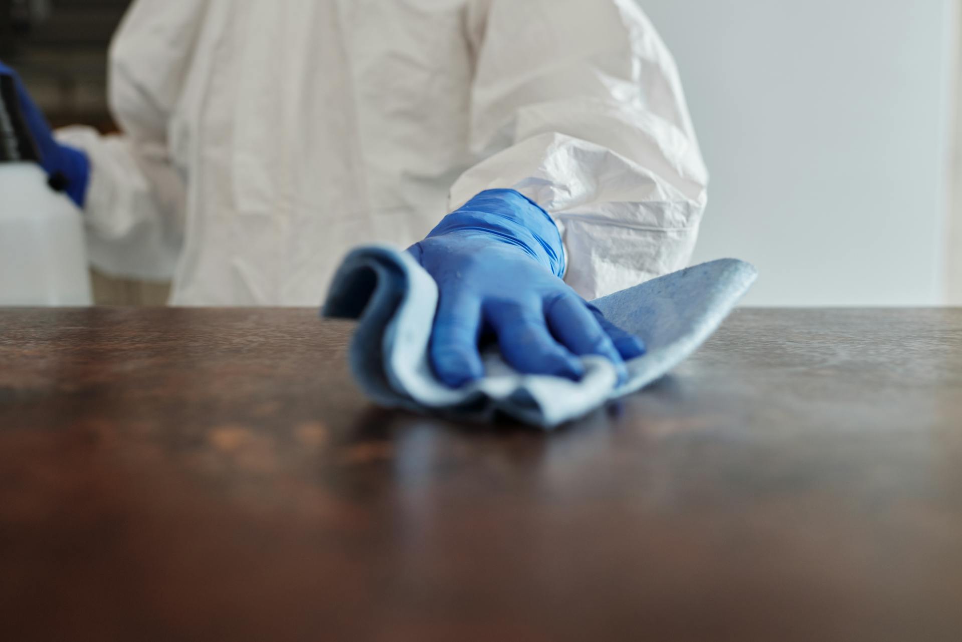 Person wearing rubber gloves, wiping down surface