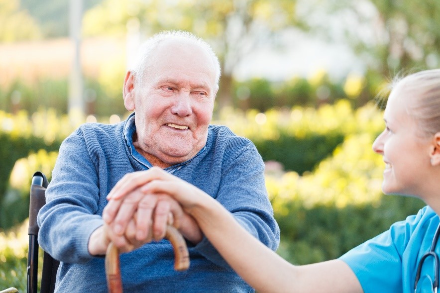 Older man sitting in wheelchair with nurse.