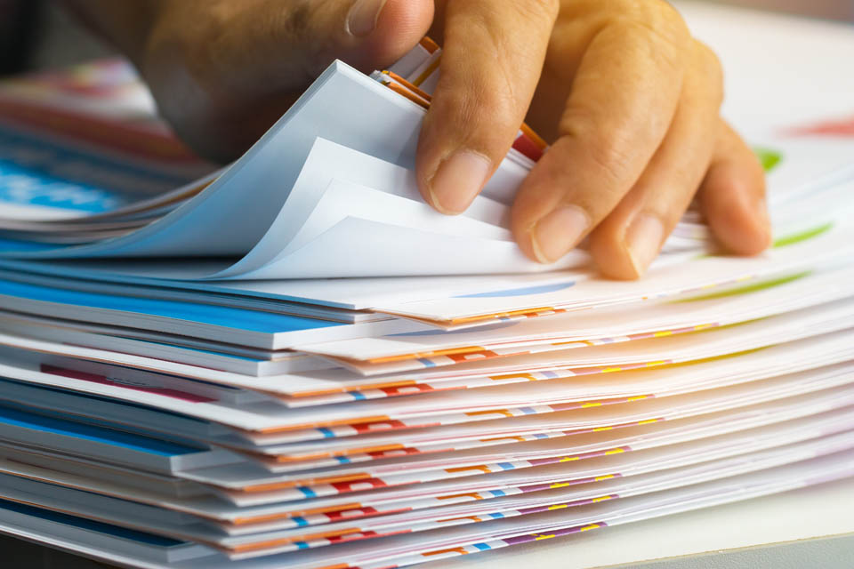 A close-up of a hand flipping through a stack of colorful documents or booklets