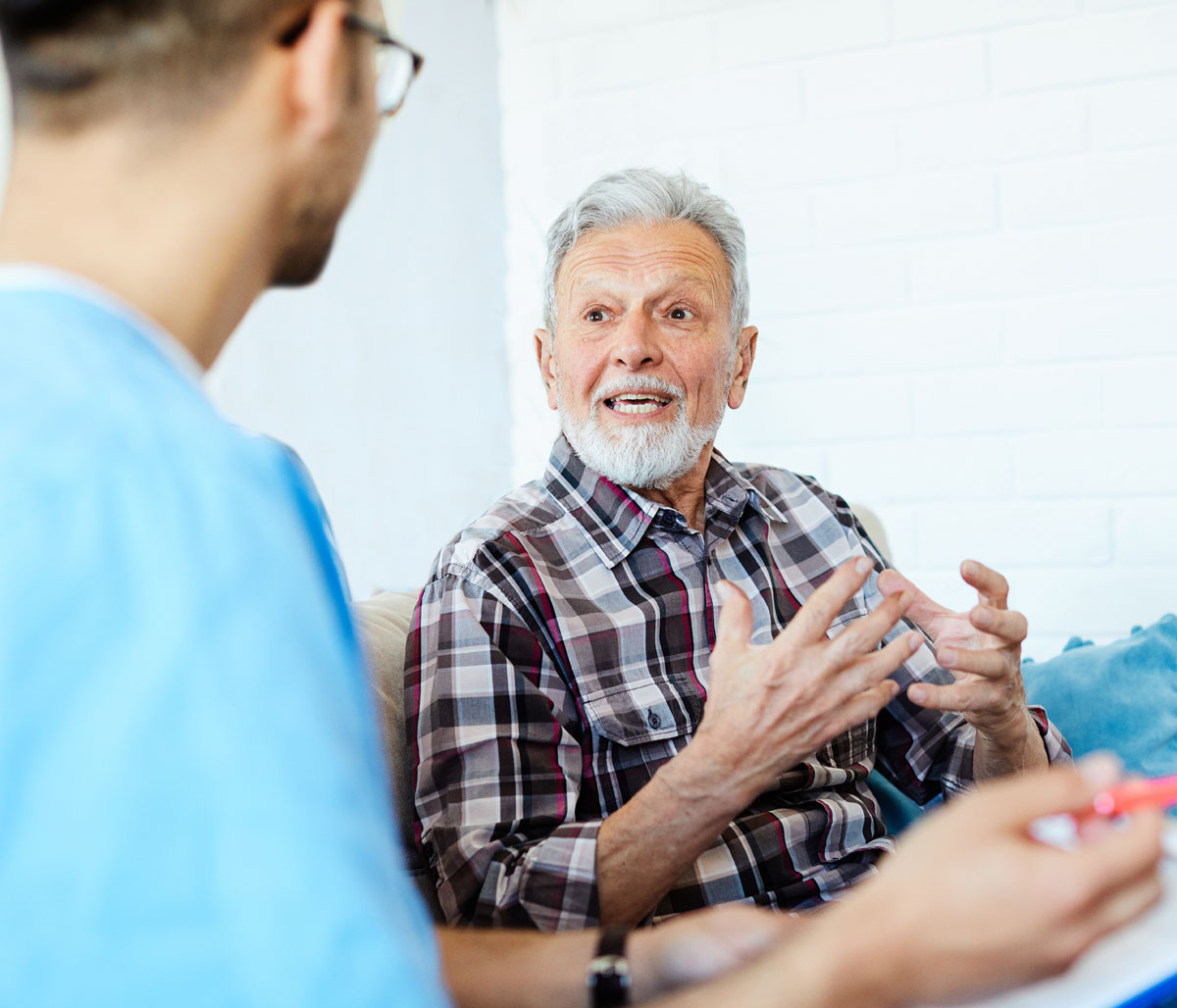 A doctor or nurse talking with a senior man who is seated
