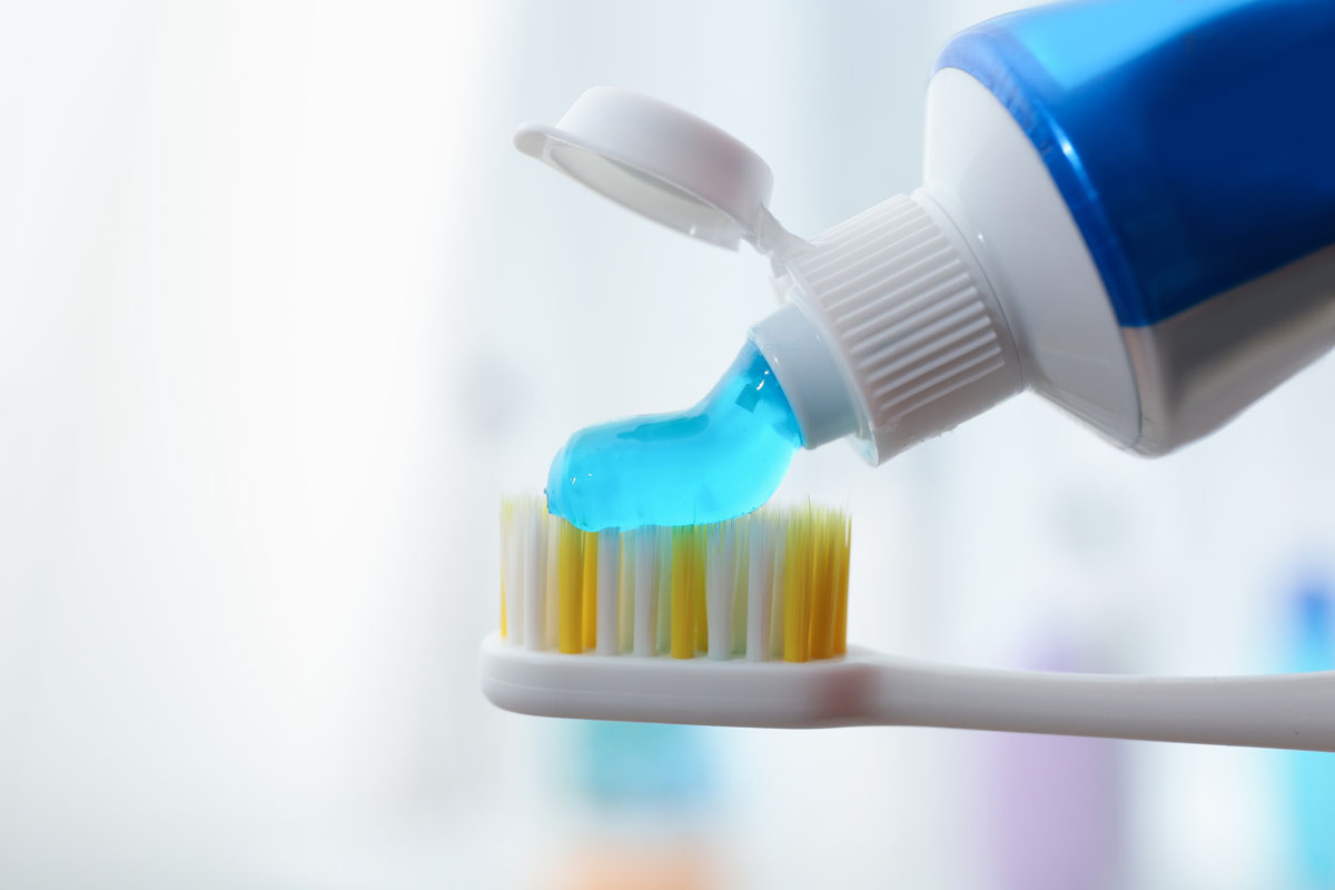 A person is applying toothpaste onto a toothbrush