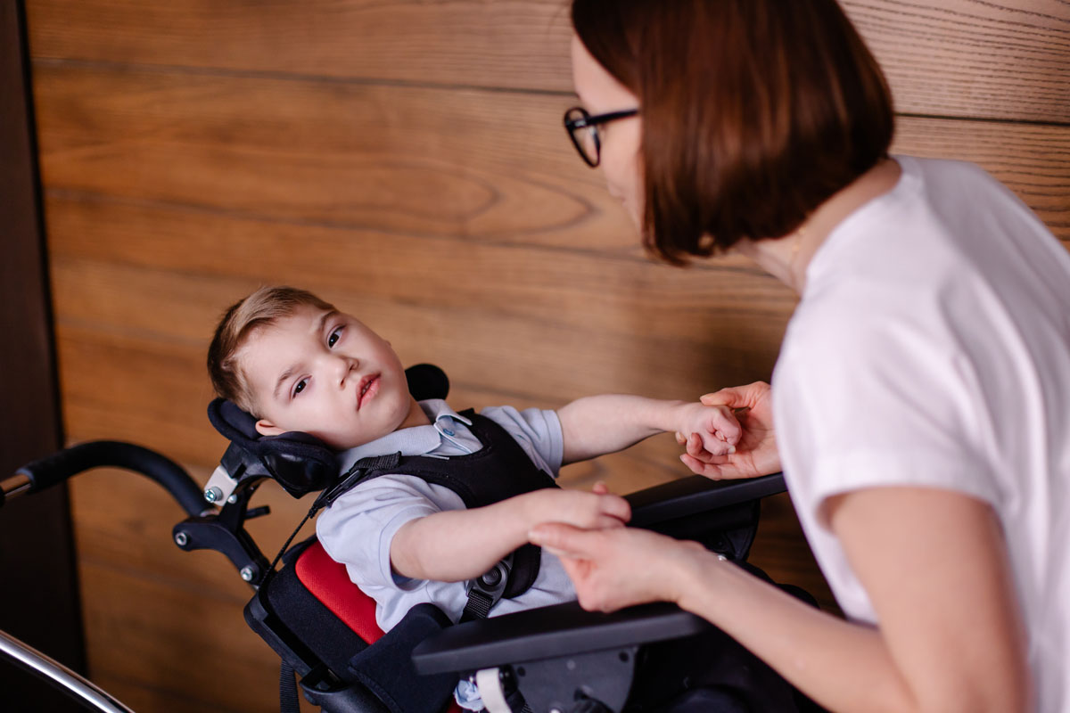 Child in a special wheelchair with cerebral palsy with his mother.
