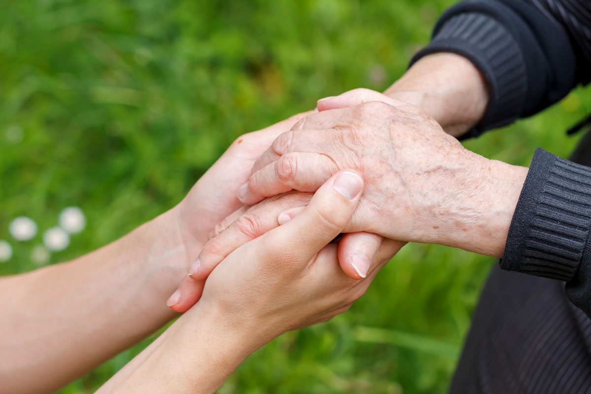 Doctor's hand holding a wrinkled elderly hand