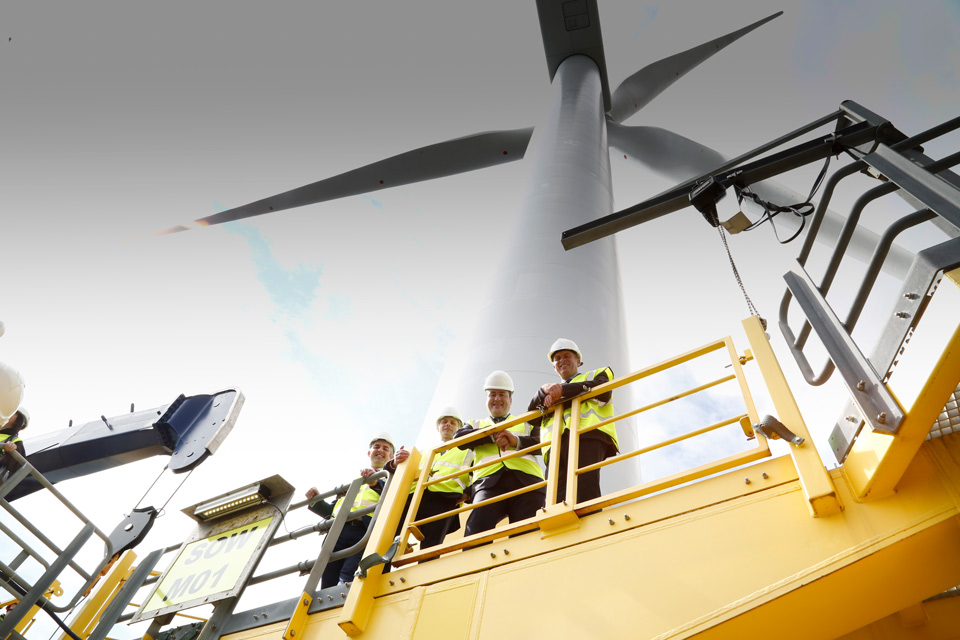 4 men in PPE standing next to a wind turbine