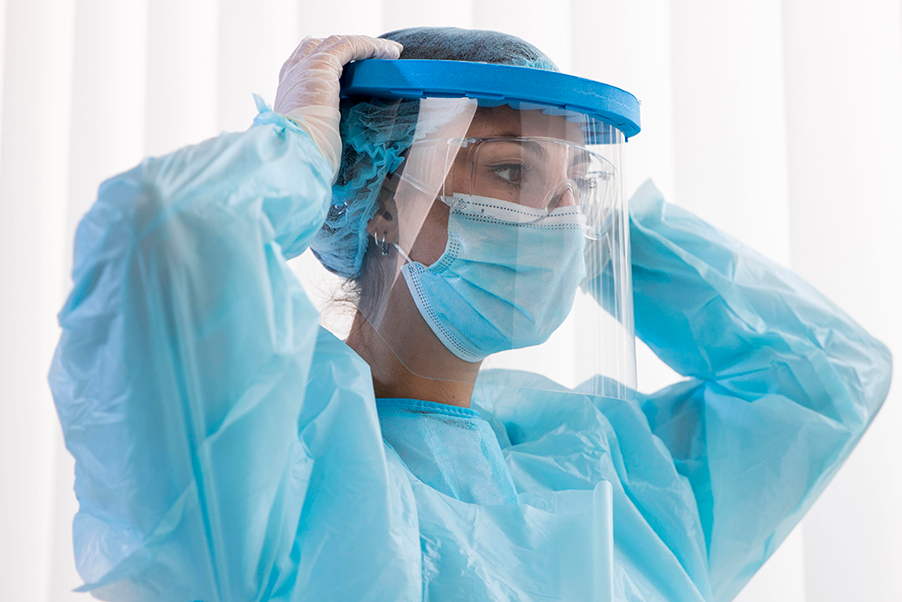 Health care worker putting on their face shield as part of the donning process