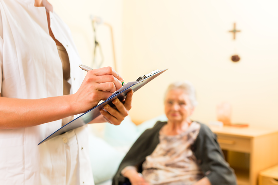 Healthcare worker writing on a clipboard while the patient is sitting down.
