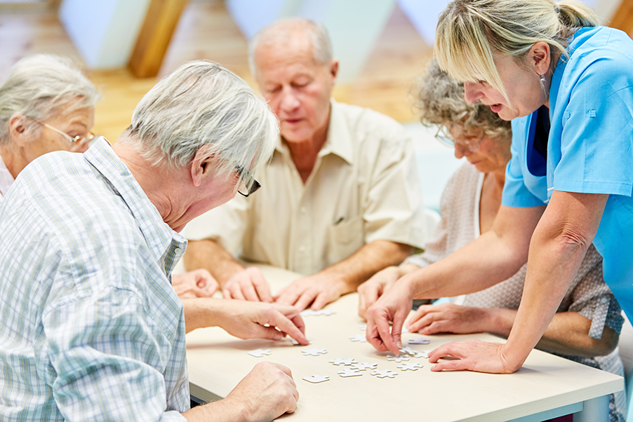 Healthcare worker and elderly people solving jigsaw puzzles