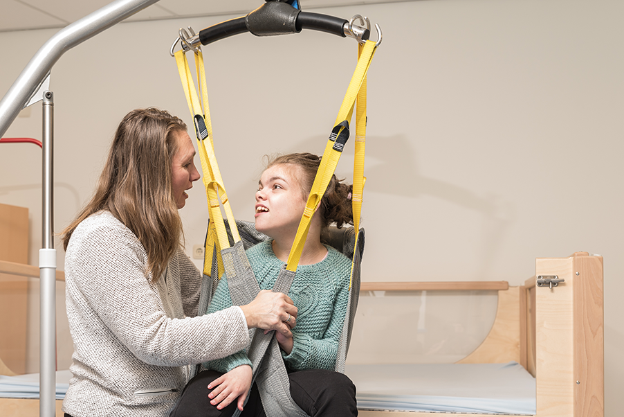 Health care worker moving patient with hoist